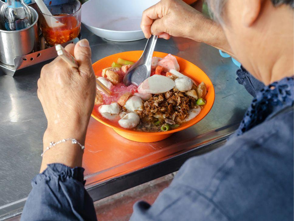 Elderly person eating a nutritious meal at a table to encourage appetite and food intake