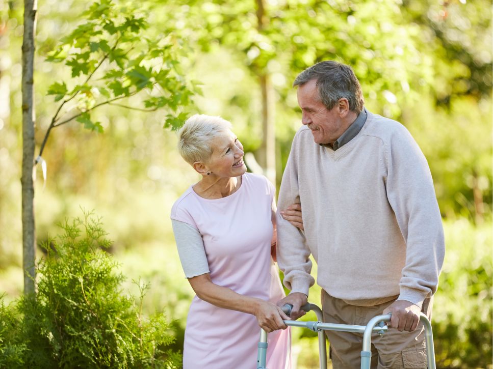 Couple âgé, dont un homme utilise une marchette, marchant ensemble à l'extérieur