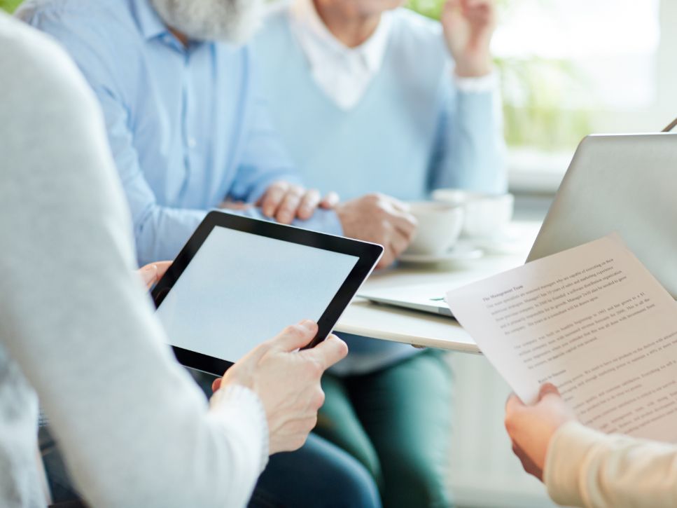 Professionnels évaluant les besoins d'une personne âgée à l'aide d'une tablette