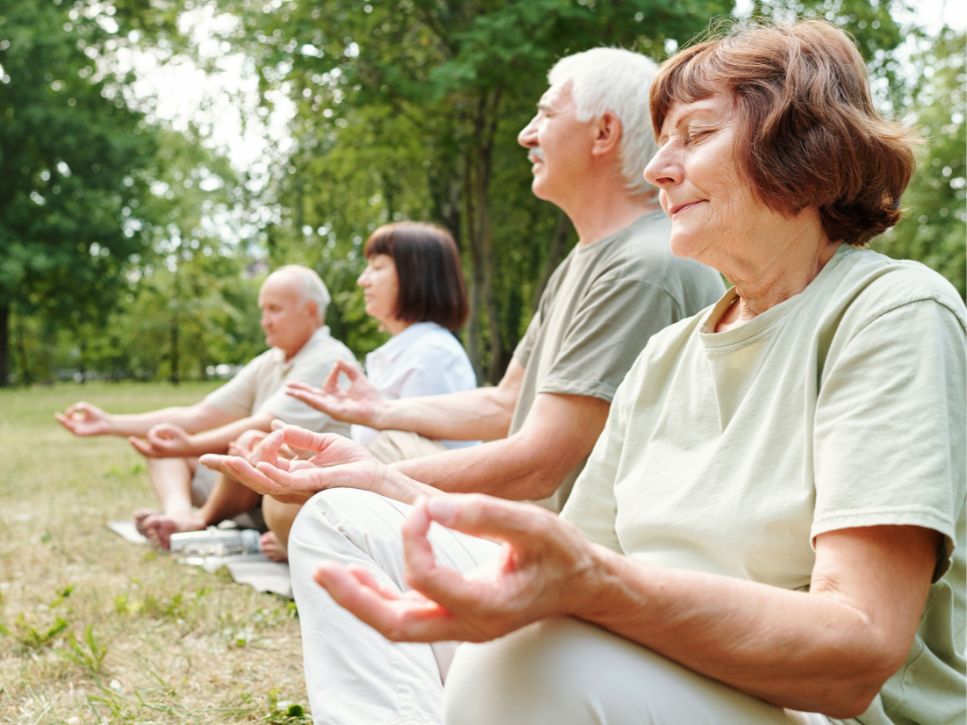 Groupe pratiquant la méditation et découvrant les bienfaits du yoga pour personnes âgées en plein air