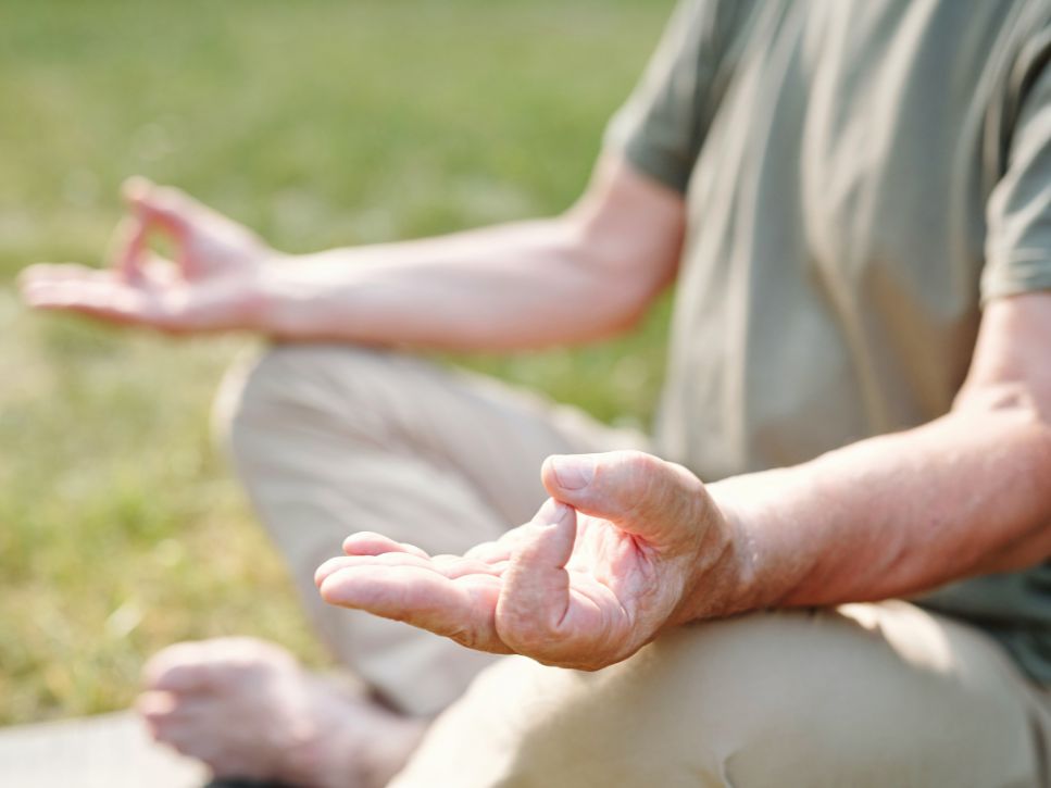Senior practising meditation outdoors in a yoga pose