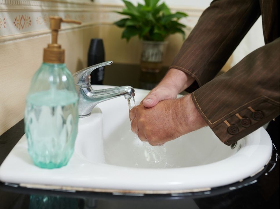 Personne âgée se lavant les mains dans la salle de bain